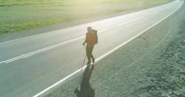 Asfalt yolda yürüyen otostopçu turist üzerinden uçuş. Yaz günü büyük bir kırsal vadi. Sırt çantalı gezgin..