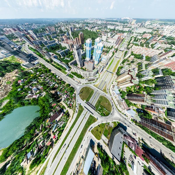 Aerial city view with crossroads and roads, houses, buildings, parks and parking lots. Sunny summer panoramic image — Stock Photo, Image