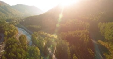 Güneşli yaz sabahında taze dağ nehri ve çayır üzerinde uçuşun ortasında. Aşağıdaki kırsal toprak yol.
