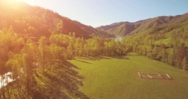 Güneşli yaz sabahında taze dağ nehri ve çayır üzerinde uçuşun ortasında. Aşağıdaki kırsal toprak yol.