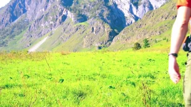 Sırt çantası ile yeşil dağ çayır üzerinde yürüyen adam hiking. Yaz spor ve eğlence kavramı. — Stok video