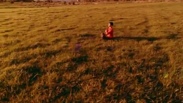 Niska wysokość lotu radialnego nad sportowcem jogi w doskonałej zielonej trawie. Zachód słońca w górach. — Wideo stockowe