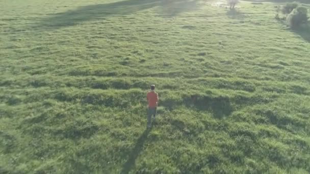 Lot nad wysportowanym mężczyzną biegającym po doskonałej zielonej trawie wiejskiej łące. Zachód słońca w górach. Surowy, płaski kolor, bez korekty. — Wideo stockowe