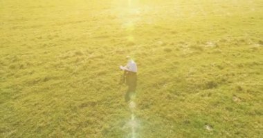 UHD 4k havadan görünümü. Defter pad ile yeşil çim sahasında oturan işadamı üzerinde düşük yörünge uçuş