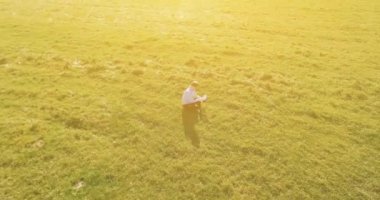 UHD 4k havadan görünümü. Defter pad ile yeşil çim sahasında oturan işadamı üzerinde düşük yörünge uçuş