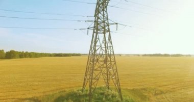 Yüksek voltajlı elektrik kulesi ve yeşil ve sarı alandaki elektrik hatları yakınında dikey hareket.