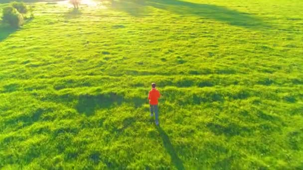Uçuş mükemmel yeşil çim kırsal çayır offroad koşan sportif adam üzerinde. Günbatımı dağ — Stok video