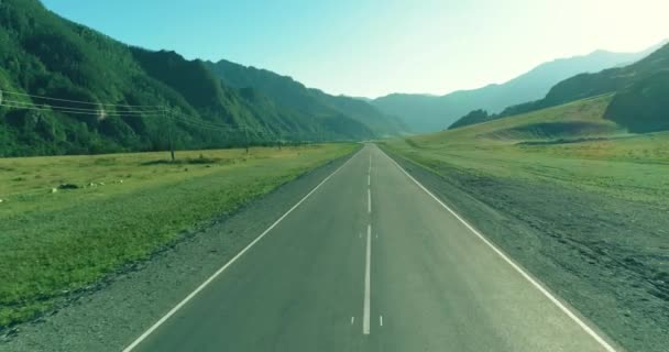 Tiefflug über Bergstraße und Wiese bei sonnigem Sommermorgen. — Stockvideo