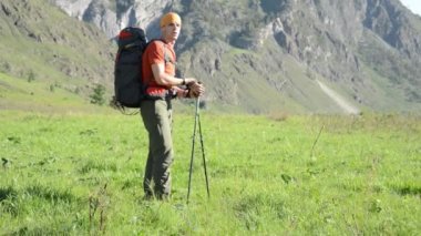 Sırt çantası ile yeşil dağ çayır üzerinde yürüyen adam hiking. Yaz spor ve eğlence kavramı.