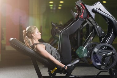 Bacaklar için ağırlıklar basın makine kullanan sportif kadın. Spor salonu.