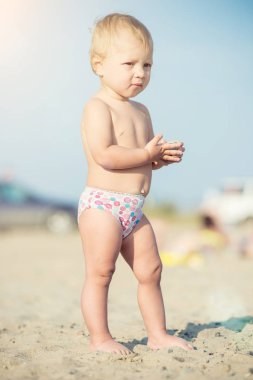 Şirin Bebek denize yakın kum plajındaki oyuncaklar ile oynama.
