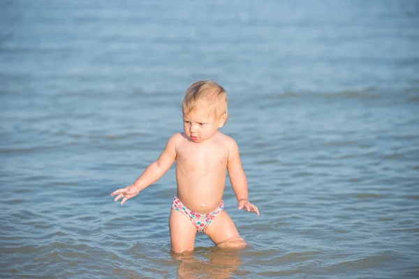 Niedliches Baby spielt am Sandstrand und im Meerwasser. — Stockfoto