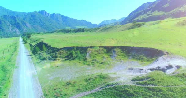 Aerial rural mountain road and meadow at sunny summer morning. Asphalt highway and river. — Stock Video