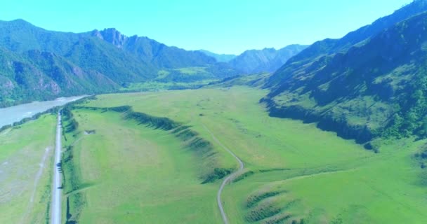 Luchtfoto landelijke bergweg en weide op zonnige zomerochtend. Asfaltweg en rivier. — Stockvideo