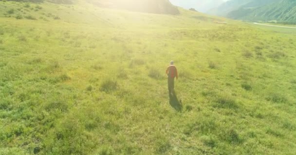 Volo sopra Zaino escursionistico turistico passeggiando attraverso il campo di montagna verde. Enorme valle rurale al giorno d'estate. — Video Stock