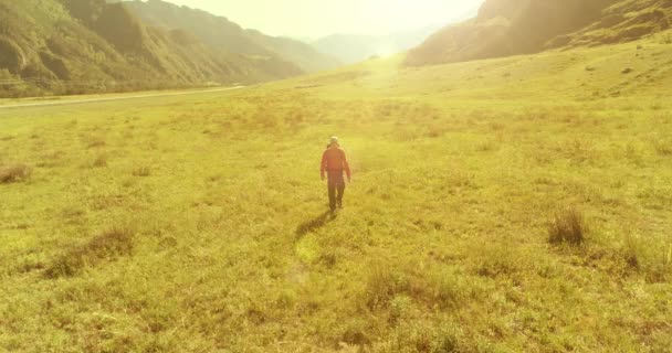 Voo sobre mochila caminhadas turista caminhando através de campo de montanha verde. Vale rural enorme no dia de verão. — Vídeo de Stock