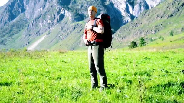 Пішохідний чоловік ходить на зеленому гірському лузі з рюкзаком. Концепція літнього спорту та відпочинку . — стокове відео