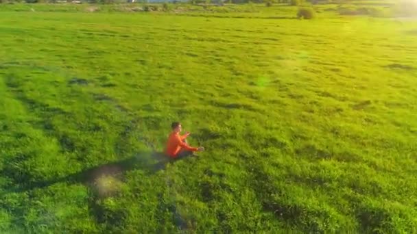 Vuelo radial de baja altitud sobre el hombre del yoga del deporte en hierba verde perfecta. Puesta de sol en montaña. — Vídeos de Stock