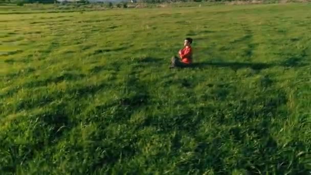 Vôo radial de baixa altitude sobre homem de ioga esporte na grama verde perfeita. Pôr do sol na montanha. — Vídeo de Stock