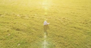 UHD 4k havadan görünümü. Defter pad ile yeşil çim sahasında oturan işadamı üzerinde düşük yörünge uçuş