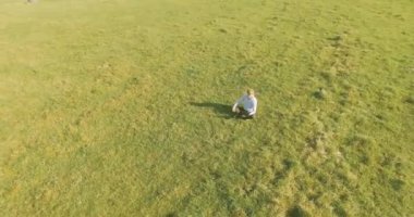 UHD 4k havadan görünümü. Defter pad ile yeşil çim sahasında oturan işadamı üzerinde düşük yörünge uçuş