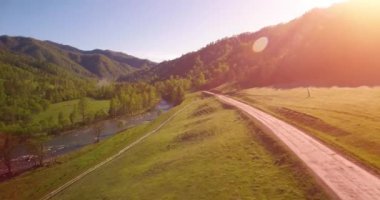 Güneşli yaz sabahında taze dağ nehri ve çayır üzerinde uçuşun ortasında. Aşağıdaki kırsal toprak yol.