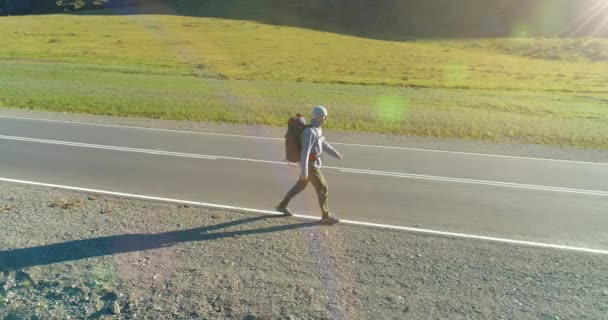 Flyg över liftare turist promenader på asfalterad väg. Enorm lantlig dal på sommardagen. Ryggsäck vandring kille. — Stockvideo