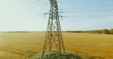 Yüksek voltajlı elektrik kulesi ve yeşil ve sarı alandaki elektrik hatları yakınında dikey hareket.