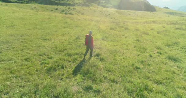 Vol au-dessus du sac à dos randonnée touristique marche à travers le champ de montagne vert. Vallée rurale énorme au jour d'été. — Video