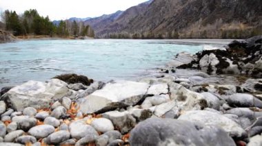 Dolly ormanın yakınındaki bir dağ nehrinde akan suyun kaygan görüntüsü. Islak kayalar ve güneş ışınları. Yatay sabit hareket.