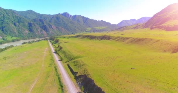 Estrada de montanha rural aérea e prado na manhã de verão ensolarada. Estrada de asfalto e rio. — Vídeo de Stock