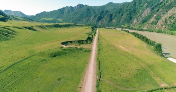 Luftlinie ländliche Bergstraße und Wiese an einem sonnigen Sommermorgen. Asphaltstraße und Fluss. — Stockvideo