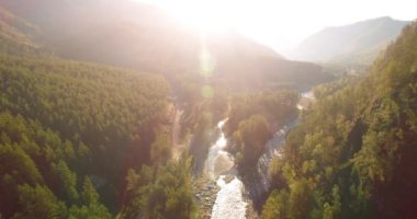 Güneşli yaz sabahında taze dağ nehri ve çayır üzerinde uçuşun ortasında. Aşağıdaki kırsal toprak yol.