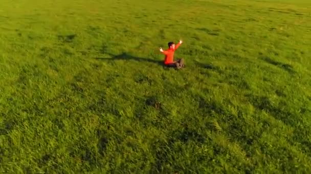 Lage hoogte radiale vlucht over sport yoga man op perfect groen gras. Zonsondergang in de bergen. — Stockvideo