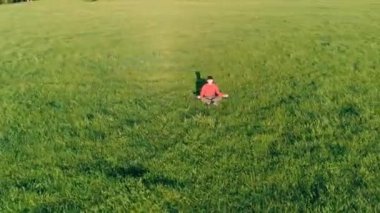 Yeşil çimlerde spor yogacısı üzerinde alçak irtifa radyal uçuş. Dağda gün batımı.