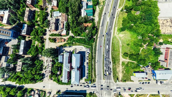 Vista aérea de la ciudad con encrucijadas y caminos, casas, edificios, parques y estacionamientos. Imagen panorámica soleada de verano —  Fotos de Stock