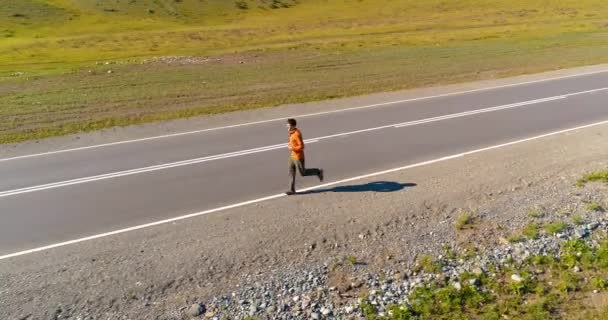 Voo de baixa altitude na frente do homem desportivo na estrada de asfalto perfeito — Vídeo de Stock