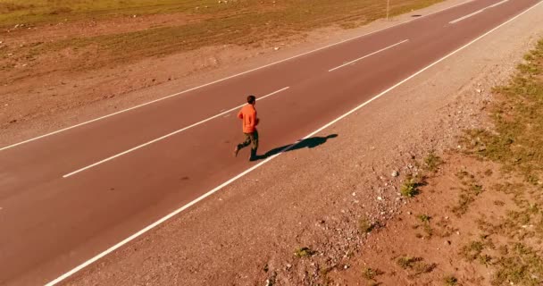 Vuelo de baja altitud frente al deportista en el camino perfecto de asfalto — Vídeo de stock