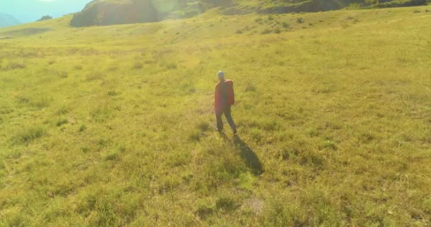 Vol au-dessus du sac à dos randonnée touristique marche à travers le champ de montagne vert. Vallée rurale énorme au jour d'été. — Video