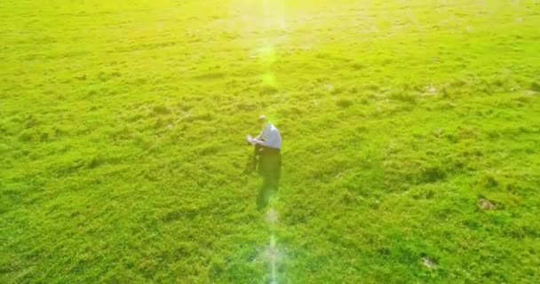 4 k Uhd 空撮。フィールド ノート パッドで緑の草の上に座ってビジネスマン上低軌道飛行 — ストック動画