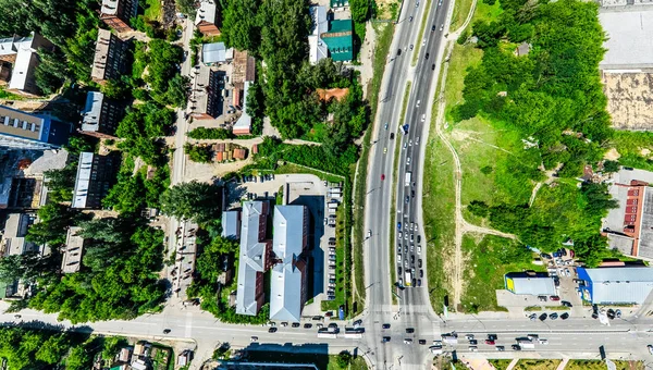 Uitzicht op de stad vanuit de lucht met kruispunten en wegen, huizen, gebouwen, parken en parkeerplaatsen. Zonnige zomer panoramisch beeld — Stockfoto