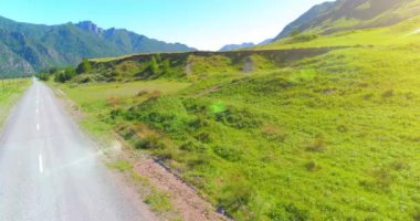 Güneşli yaz sabahında havadan kırsal dağ yolu ve çayır. Asfalt karayolu ve nehir.