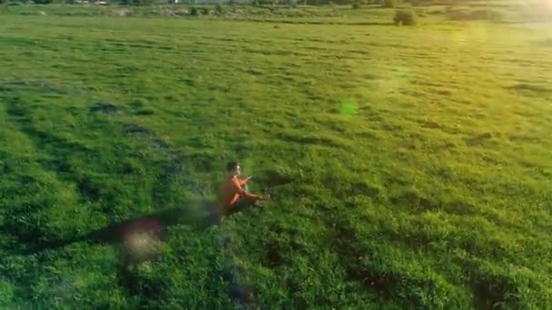 Vuelo radial de baja altitud sobre el hombre del yoga del deporte en hierba verde perfecta. Puesta de sol en montaña. — Vídeos de Stock