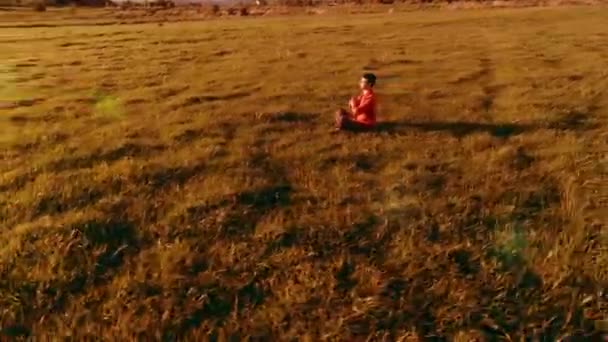 Vôo radial de baixa altitude sobre homem de ioga esporte na grama verde perfeita. Pôr do sol na montanha. — Vídeo de Stock