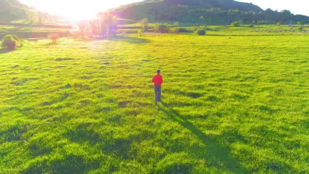 Flight over sport man at perfect green grass meadow. Sunset in mountain — Stock Video