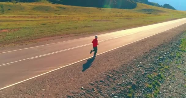 Vuelo de baja altitud frente al deportista en el camino perfecto de asfalto — Vídeo de stock