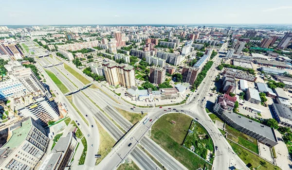 Vista aérea de la ciudad con encrucijadas y caminos, casas, edificios, parques y estacionamientos. Imagen panorámica soleada de verano — Foto de Stock