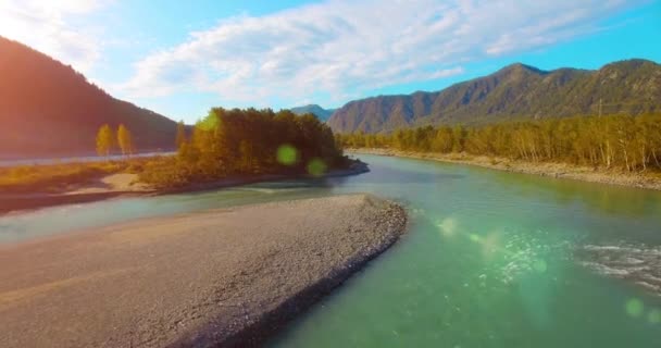 4k UHD flygvy. Lågt flyg över färsk kall fjällälv på solig sommarmorgon. Gröna träd och solstrålar på horisonten — Stockvideo