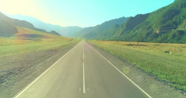 Vuelo aéreo de baja altura sobre carretera de montaña y prado en la soleada mañana de verano . — Vídeos de Stock