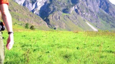 Sırt çantası ile yeşil dağ çayır üzerinde yürüyen adam hiking. Yaz spor ve eğlence kavramı.